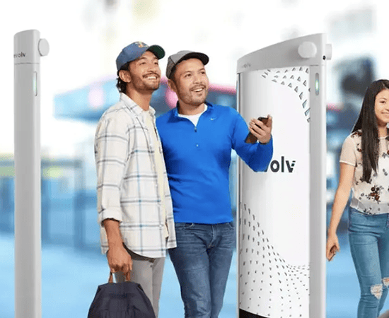 People happily passing through Evolv Express security scanners, showcasing smart IoT technology.