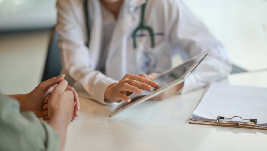 doctor-and-patient-sitting-at-table-reviewing-tablet